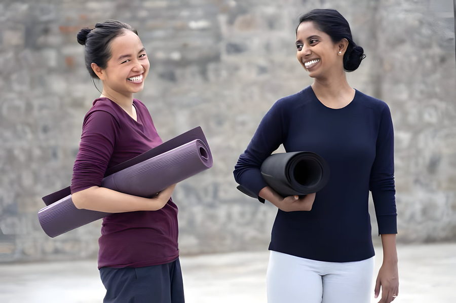 Two women smiling with yoga mats