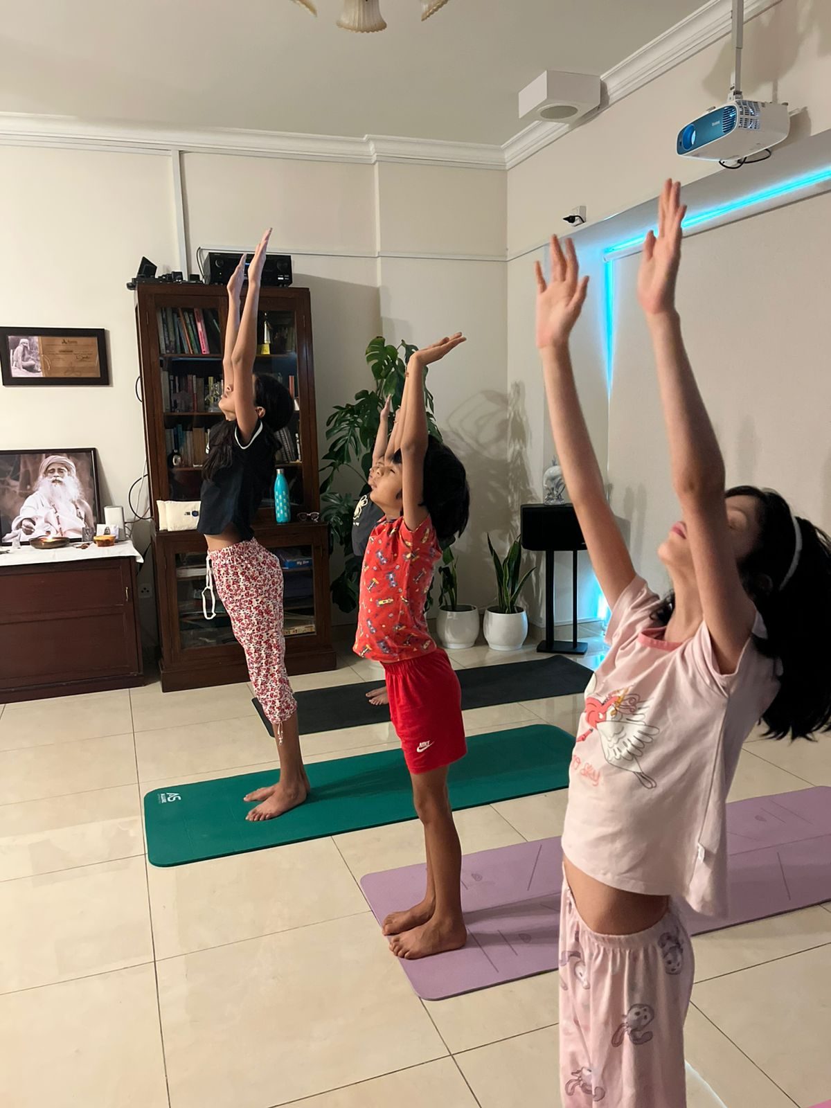 Three children standing on their mats with arms stretched overhead