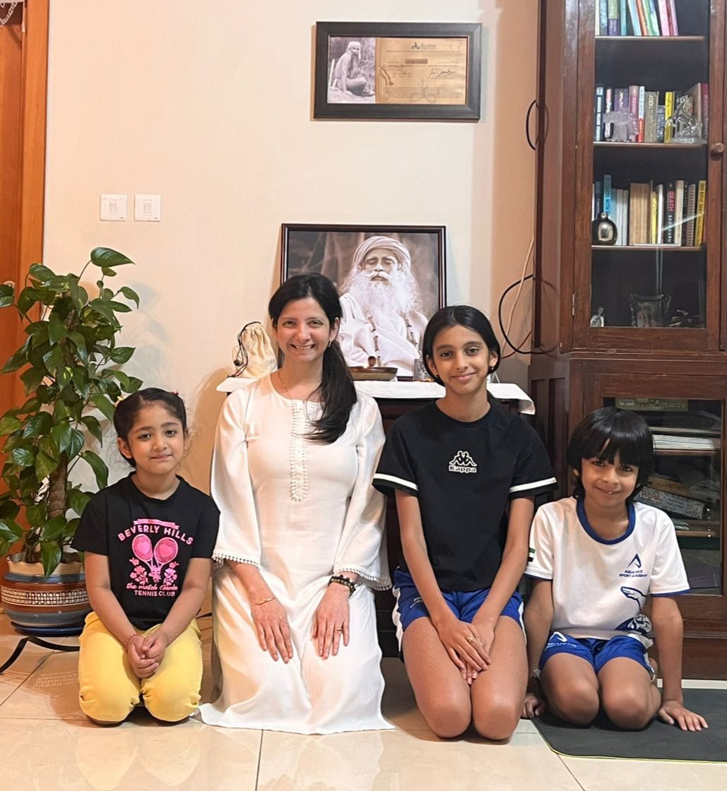 Persis in white kneeling with four smiling children in the studio