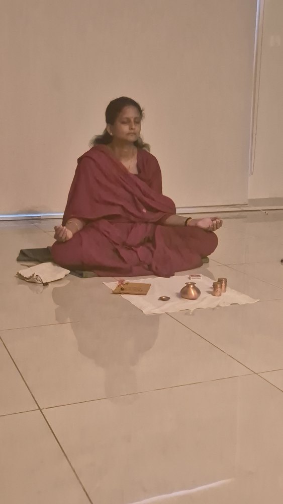 An adult student seated cross-legged on the studio floor with the practice laid out in front of her