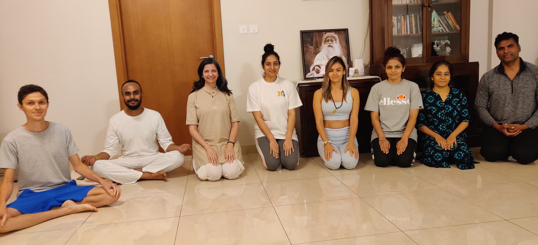 Nine adult students seated and kneeling across the studio floor with Persis at the end of a class